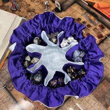 Load image into Gallery viewer, A light blue and purple dice bag sits open on a gaming table. Inside, the individual pockets are filled with dice.