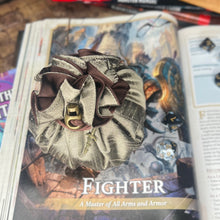 Load image into Gallery viewer, A bronze and brown dice bag is closed on a gaming table with a dice tray and D&D books in the background.