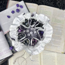 Load image into Gallery viewer, A silver and white dice bag is open on top of D&D gaming books. Inside, the pockets are filled with colorful dice.