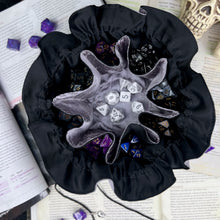 Load image into Gallery viewer, A silver and black dice bag is open on top of D&D game books. Inside, the pockets are full of colorful dice.
