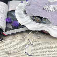 Load image into Gallery viewer, A silver and white dice bag with a metal moon charm is open flat on top of D&amp;D gaming books.
