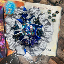 Load image into Gallery viewer, A blue and silver dice bag is open on a gaming table with a dice tray and D&amp;D books in the background.
