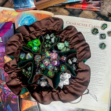 Load image into Gallery viewer, A green and brown dice bag is closed on a gaming table with a dice tray and D&amp;D books in the background.
