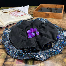 Load image into Gallery viewer, A black and shimmering dice bag sits open flat on a gaming table.
