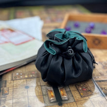 Load image into Gallery viewer, A black and green dice bag sits closed on top of a D&amp;D map.
