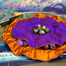 Load image into Gallery viewer, A purple and orange dice bag lays open on a gaming table.
